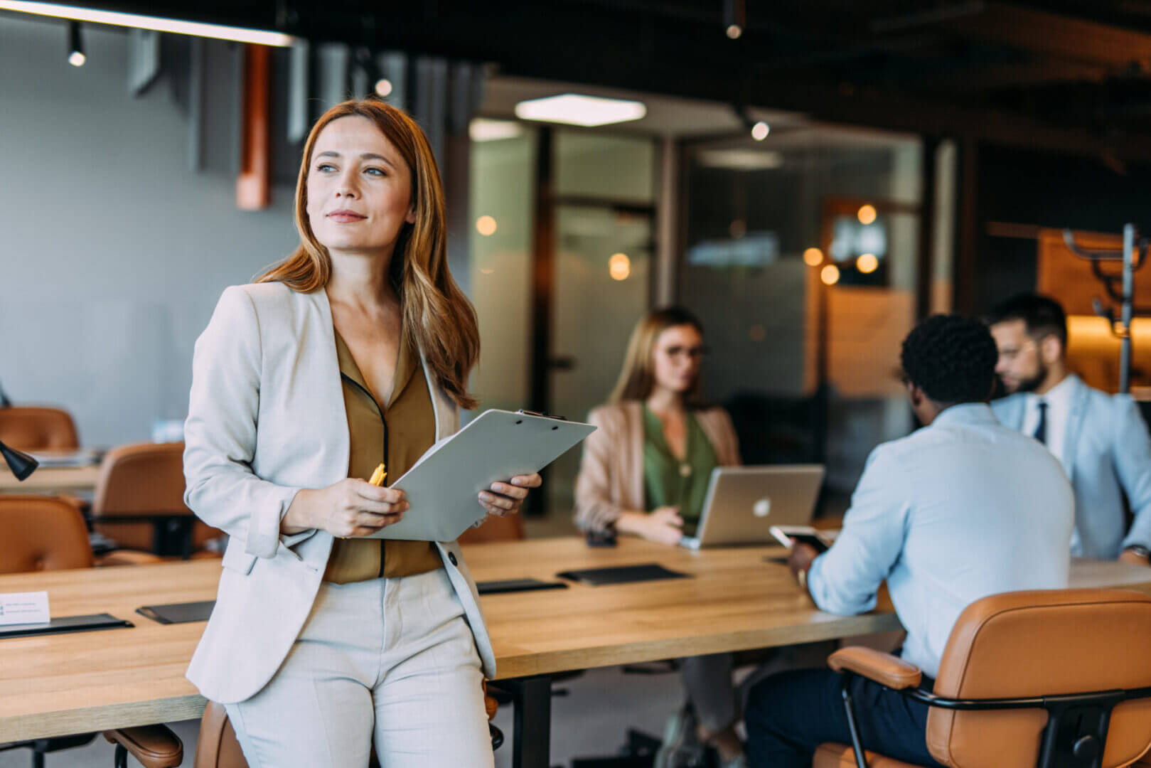 Businesswoman holding clipboard in meeting room.